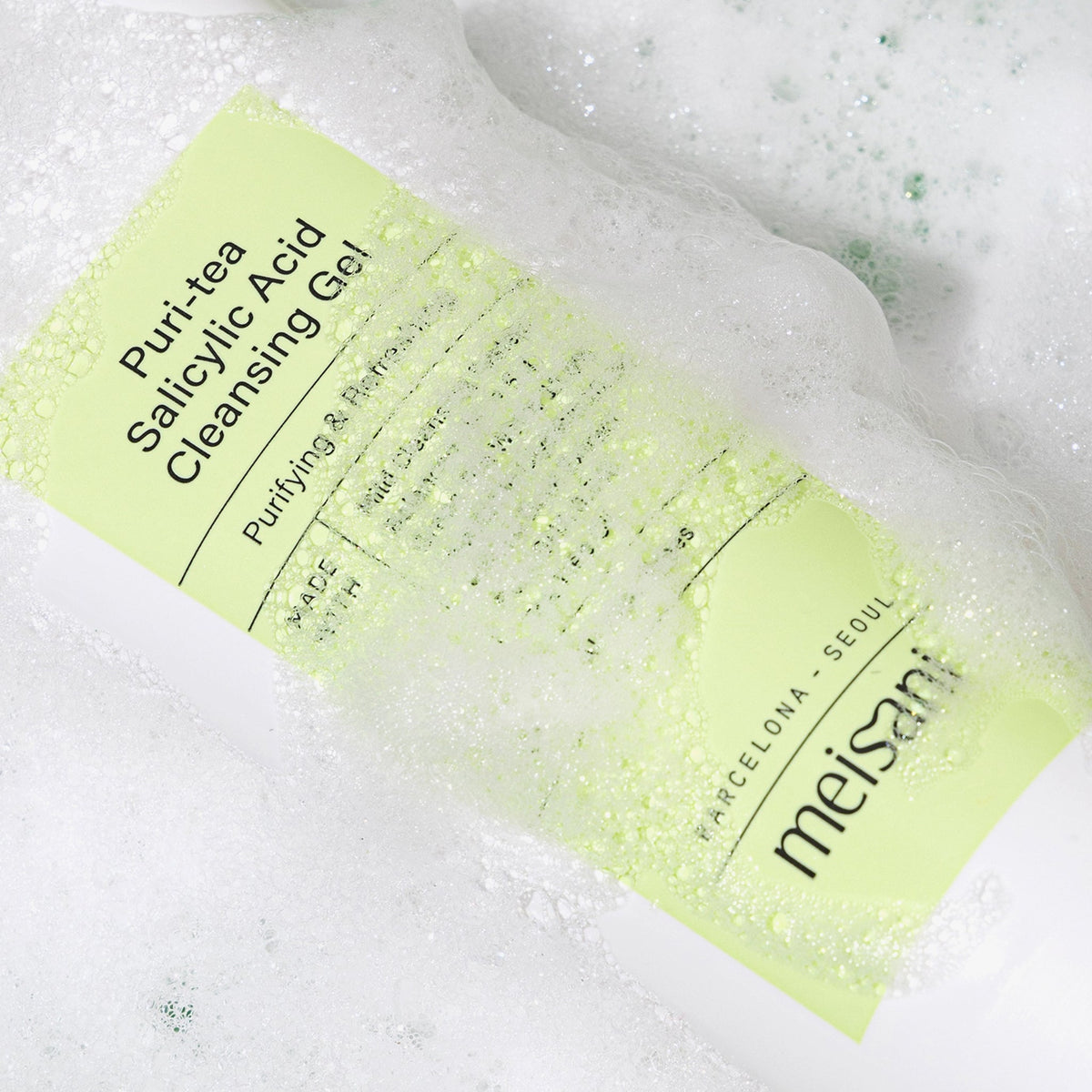 Eine hellgrüne Tube meisani Puri-Tea Salicylsäure-Reinigungsgel liegt im Wasser und ist überzogen mit Schaum.