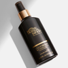 Eine dunkelbraune Flasche Liquid Gold Dry Oil von Bondi Sands mit goldenen Details liegt auf weißer Oberfläche