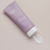 Lilafarbene Tube mit 2 % BHA Body Spot Exfoliant von Paula’s Choice, wobei das Produkt auf eine beige Oberfläche gedrückt wurde.