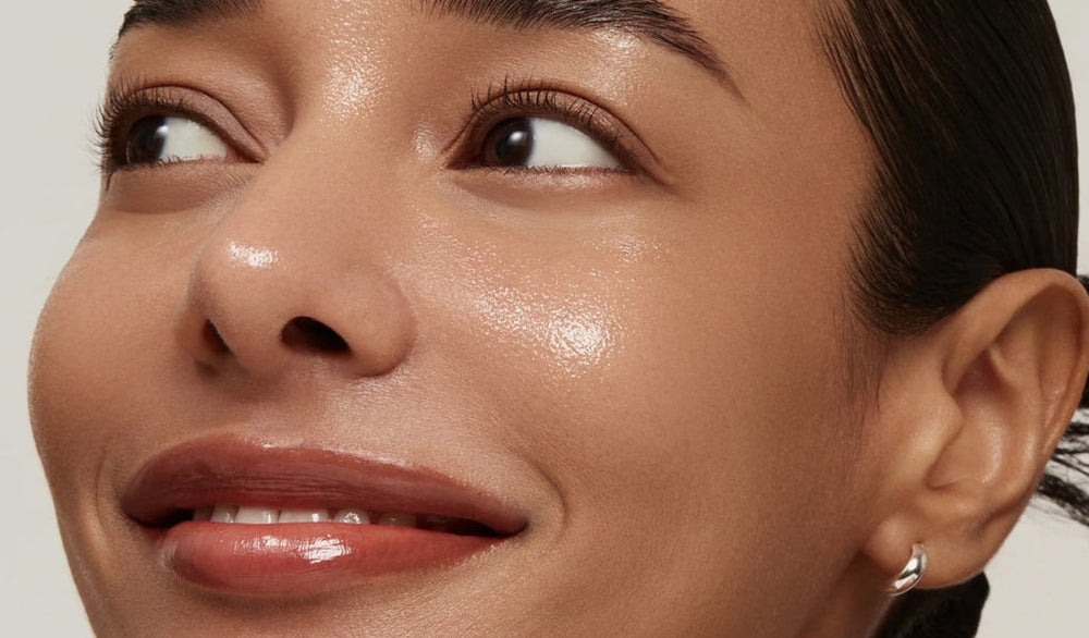 Nahaufnahme des Gesichts einer lächelnden Frau mit dem "Glass Skin"-Look: Ihre Haut ist sehr glänzend und ihre Lippen glänzen.