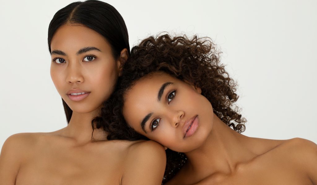 Zwei Frauen mit dunklen Features vor weißem Hintergrund.