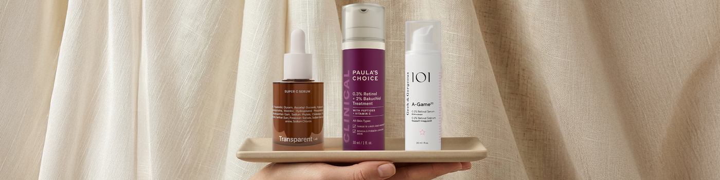 Eine Person trägt mit geschlossenen Augen lächelnd Creme auf ihre Wange auf, vor einem dunklen Hintergrund.