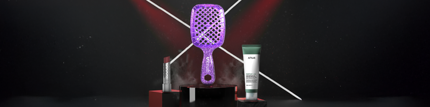 Eine glitzernde lila Haarbürste, ein Lippenstift und eine Cremetube, die auf dunklen Podesten mit roten Lichtern ausgestellt sind.