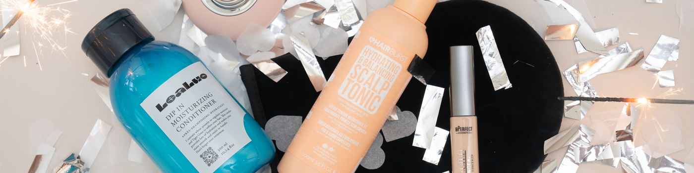 Beautyprodukte von LeaLuo, HAIRBURST und BPerfect auf grauer Oberfläche mit silbernem Konfetti.