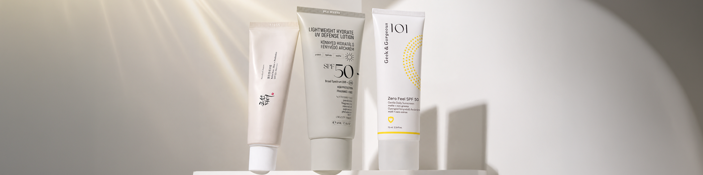 Eine Person trägt Sonnenschutzlotion auf Schulter und Dekolleté auf und hält dabei eine blaue Flasche von Ultra Violette SPF 50+.
