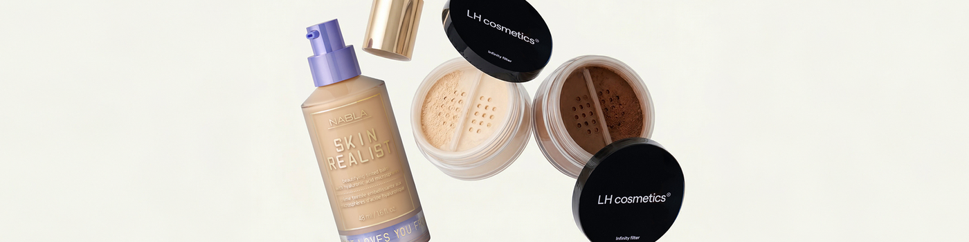 Eine Flasche mit flüssiger Grundierung und zwei Puderdosen mit schwarzen Deckeln mit der Aufschrift LH cosmetics auf hellem Hintergrund.