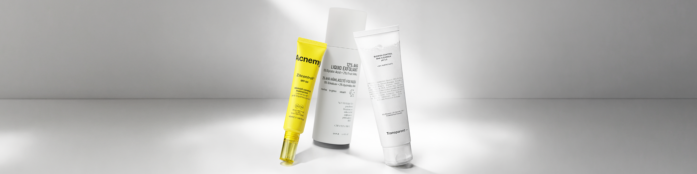Drei Tuben mit Hautpflegeprodukten, eine gelbe und zwei weiße, stehen aufrecht auf einer weißen Fläche mit sanfter Beleuchtung.