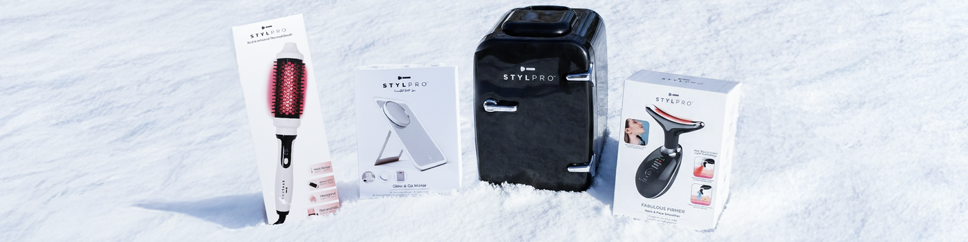 Verschiedene Schönheitsgeräte und Hautpflegetools, darunter eine LED-Maske, auf rosa Hintergrund präsentiert.