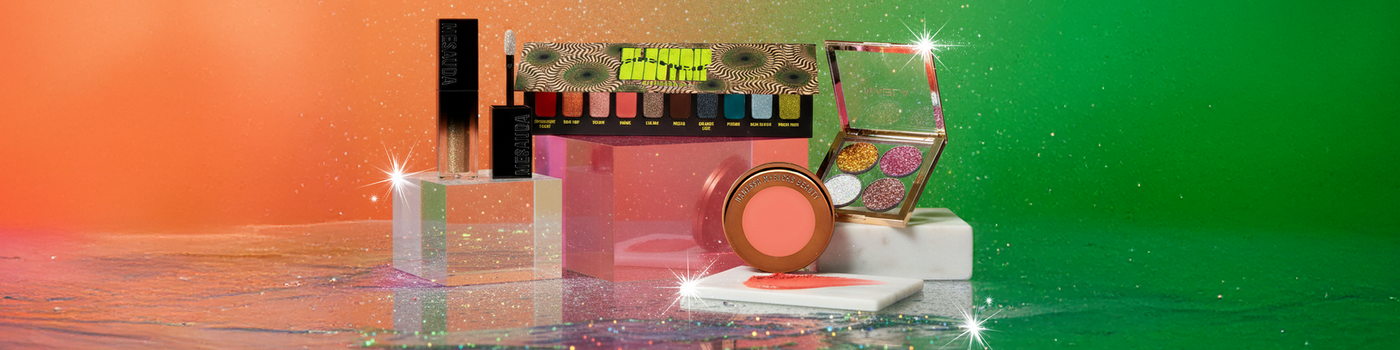 Verschiedene bunte Make-up-Produkte auf Blöcken mit Glitzereffekten und einem leuchtenden orange-grünen Hintergrund.