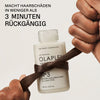 Eine Flasche OLAPLEX N°3 Hair Perfector umknotet von einem braunen Haarstrang; Text besagt: "Macht Haarschäden in weniger als 3 Minuten rückgängig"