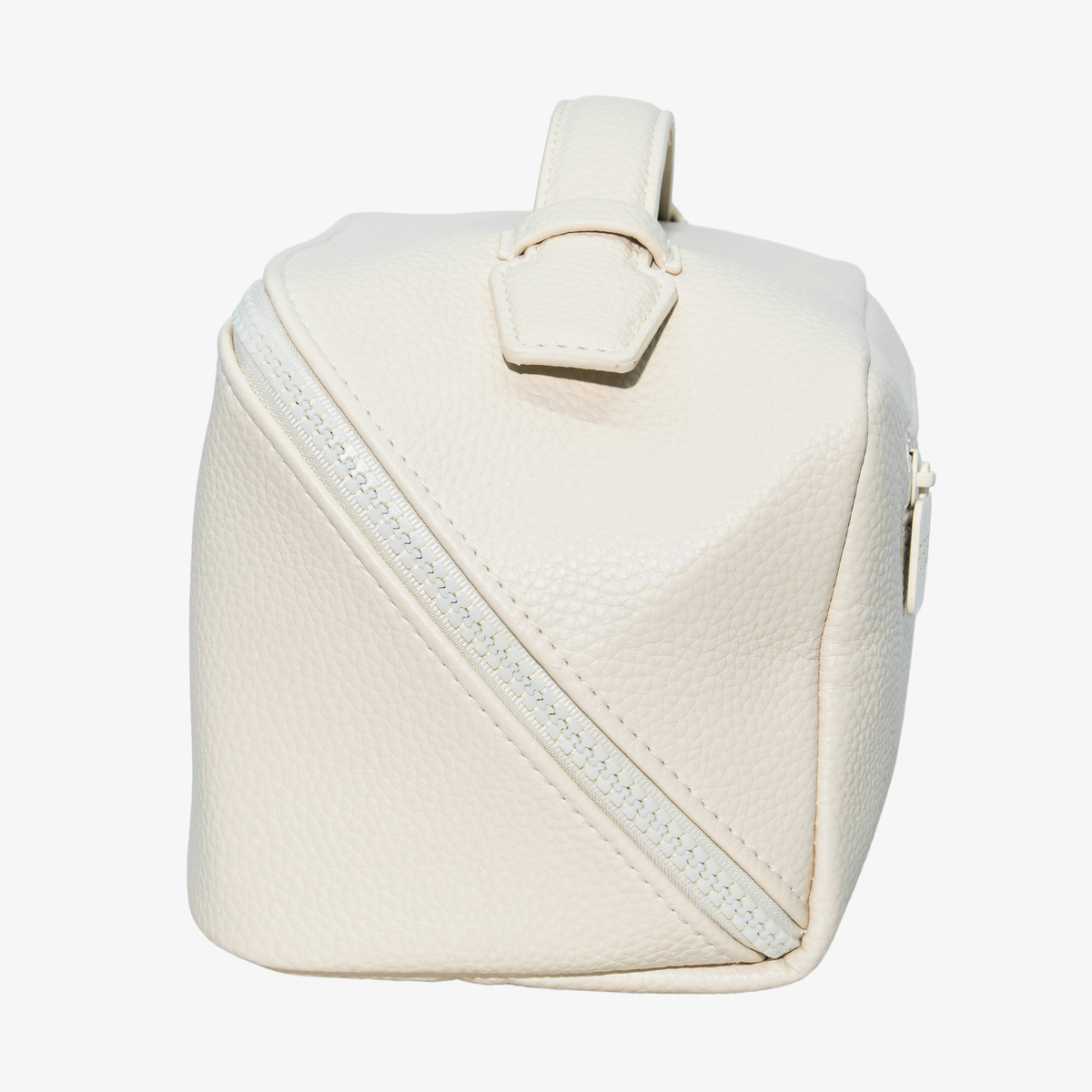 PURISH Reisetasche – Creme: Eine cremefarbene Tasche aus strukturiertem Leder mit diagonalem Reißverschluss und Tragegriff von PURISH, hier auf weißem Hintergrund abgebildet.