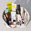 Offene „Purish Favorites“-Tasche von PURISH auf Fliesen, gefüllt mit Beauty-Produkten und einem gut sichtbaren 10-Euro-Geschenkgutschein.