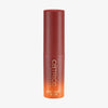 Roter Catrice Jelly Glow Stick mit Farbverlauf in Orange und goldener Aufschrift. Der Stick ist geschlossen und steht aufrecht vor hellem Hintergrund.