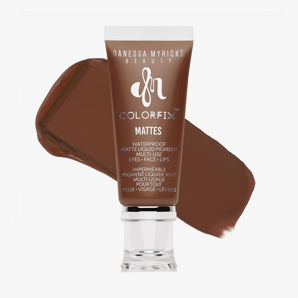 Eine braune Tube von Danessa Myricks Beauty Colorfix Mattes in Chestnut mit einem kastanienfarbenen Pigmentmuster dahinter.