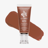 Eine Tube Danessa Myricks Beauty Colorfix Mattes in Rustic, mit einem Abstrich des braunen Pigments im Hintergrund.