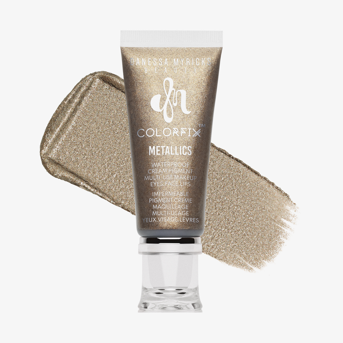 Eine Tube Danessa Myricks Beauty Colorfix Metallics in Iconic, mit einem schimmernden Goldmuster dahinter.