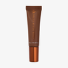 Eine braune Tube „Danessa Myricks Beauty Glosswork 4D Ultra Shine Plumping Gloss“ mit kupferfarbener Verschlusskappe und der Aufschrift „10 ml (0,34 fl oz)“.