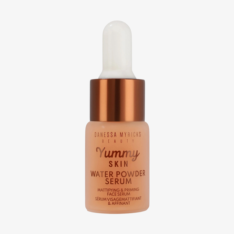 Eine Tropfflasche „Danessa Myricks Beauty Yummy Skin Water Powder Serum Deluxe“ mit einem kupferfarbenen Verschluss.
