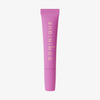Eine rosafarbene Tube Dominique Cosmetics Juicy Lip Balm steht aufrecht auf einem weißen Hintergrund, das goldene Etikett "DOMINIQUE" ist sichtbar.