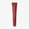 Eine rote Juicy Lip Balm Tube von Dominique Cosmetics mit vertikaler beiger Schrift auf weißem Hintergrund.
