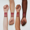 Drei Arme mit unterschiedlichen Hauttönen zeigen Swatches der 8h matte comfort lipliner shades von Essence auf ihren inneren Unterarmen.