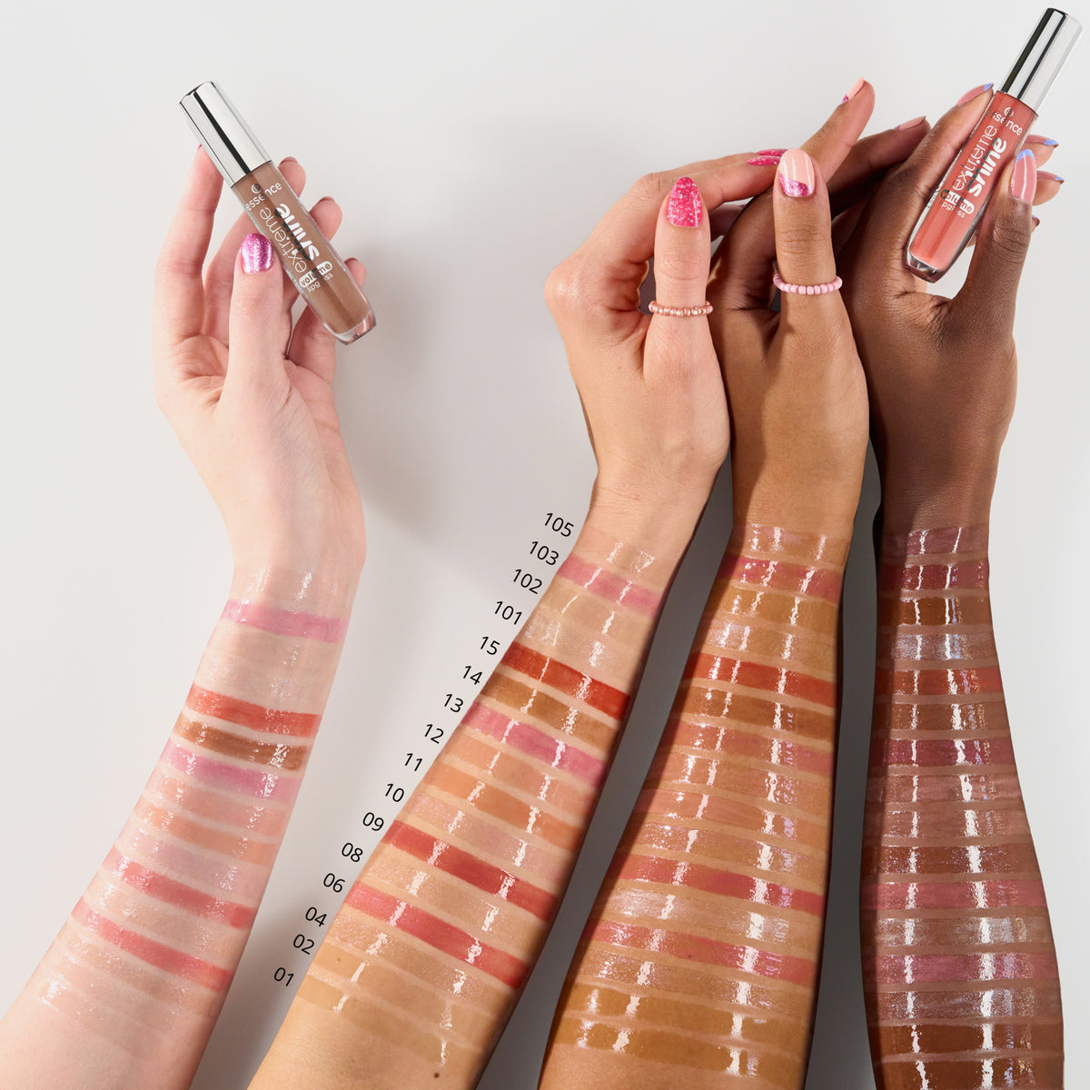 Drei Arme mit unterschiedlichen Hauttönen zeigen Muster der Essence Extreme Shine Volume Lipgloss-Farben, nummeriert von 01 bis 15.