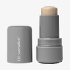 Ein grauer LH Cosmetics Artistick Highlighter mit abgenommener Kappe, die den beigen Highlighter im Inneren zeigt.