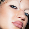Nahaufnahme von blauen Augen, dramatischem Eyeliner und nudefarbenem Lippenstift mit The Single von LH Cosmetics.