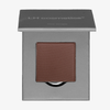 Ein einzelner brauner Puderlidschatten in einer teilweise geöffneten grauen LH Cosmetics "The single"-Dose.