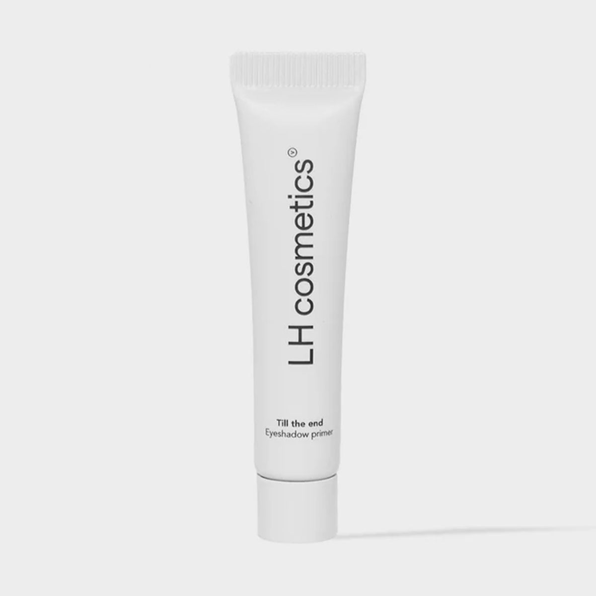 Eine weiße Tube mit der Aufschrift "LH Cosmetics Till The End Eyeshadow Primer" wird vor einem schlichten hellen Hintergrund gezeigt.