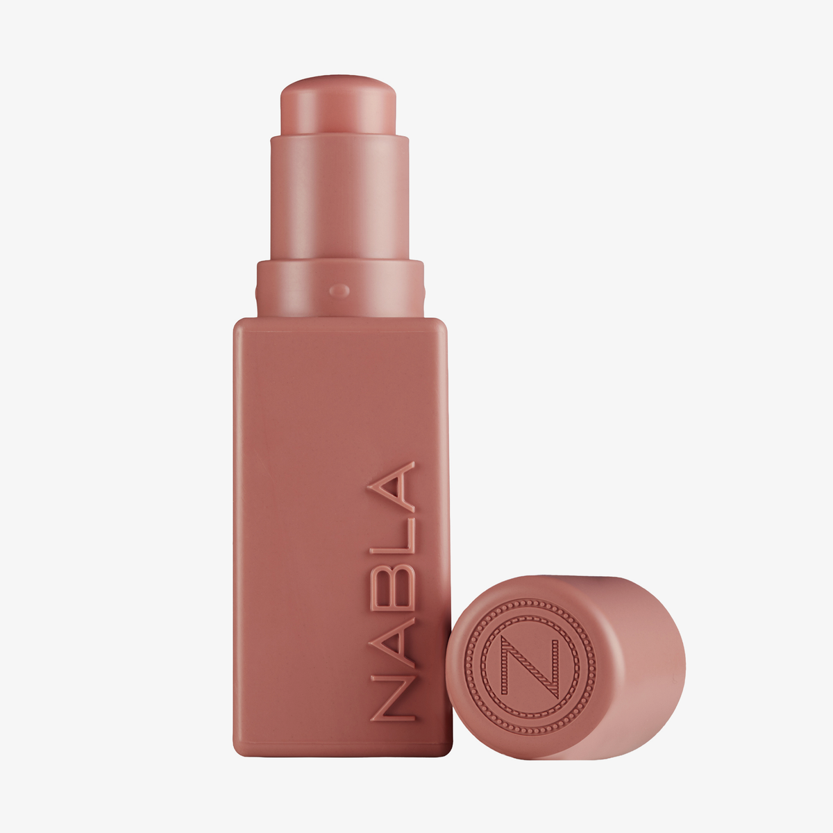 Ein mauvefarbener „Art Of Skin Blush Stick“ Chamomille von NABLA Cosmetics mit einer dazu passenden Kappe daneben.