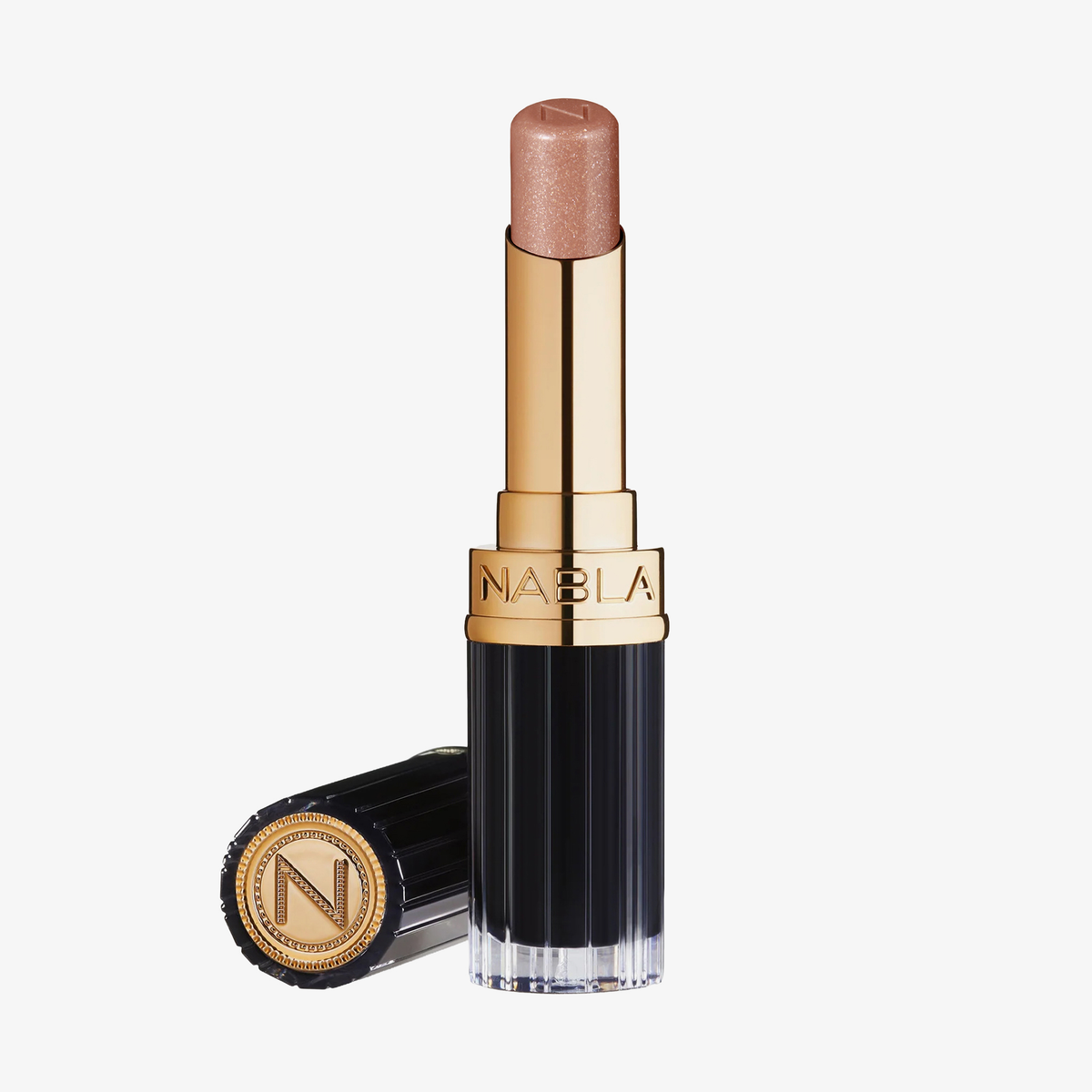 Ein NABLA Cosmetics Beyond Jelly Lipstick Perlati Crystal Bliss in Gold und Schwarz, mit einem schimmernden Nude-Ton, neben seiner flachen Kappe.
