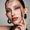 Frau mit grafischem Eyeliner und geglättetem Haar trägt NABLA Cosmetics Cupids Arrow Micro mit einem Schminkpinsel auf.