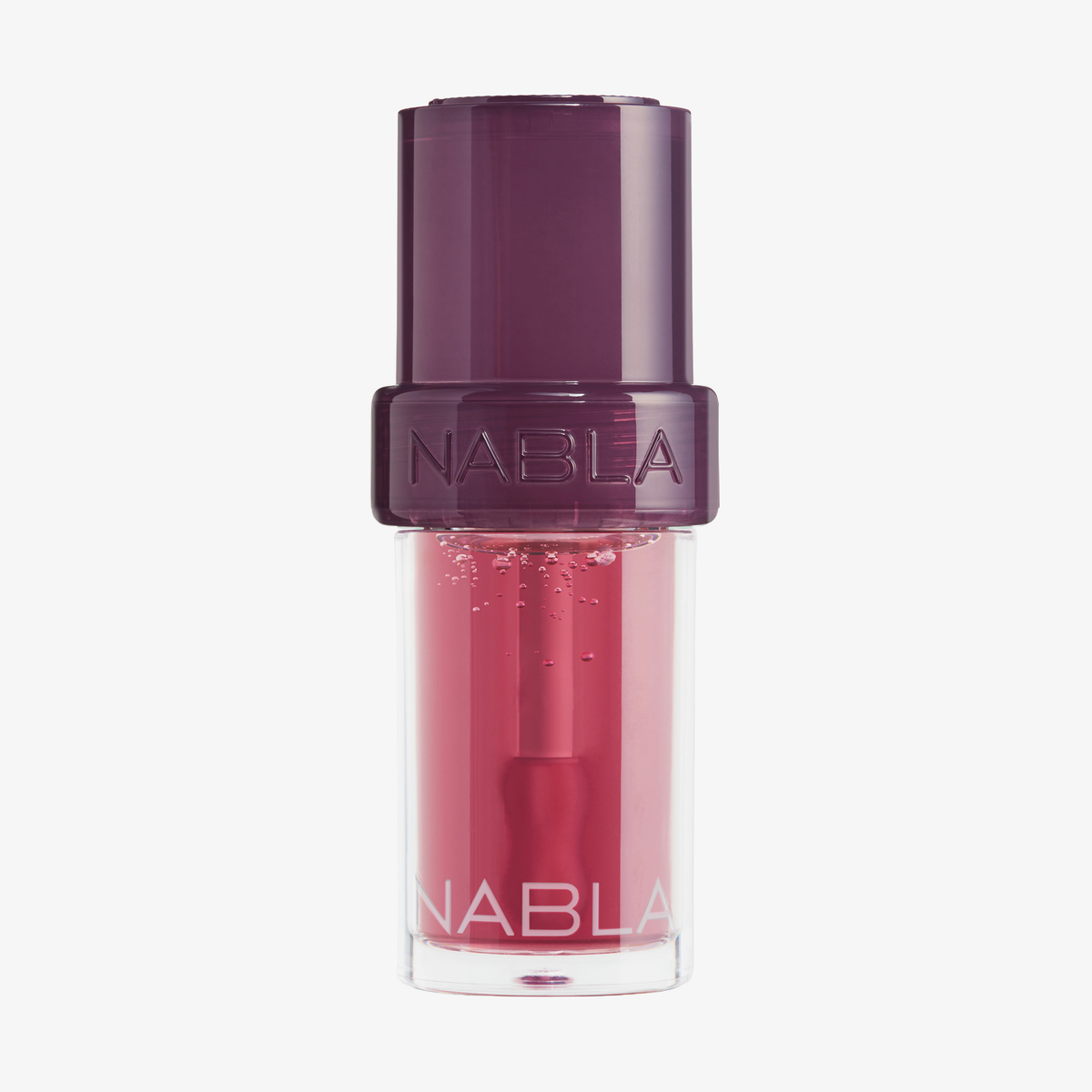 Ein „Lip Candy Oil“ Fig von NABLA Cosmetics mit einer tiefvioletten Kappe und einem durchsichtigen Flakon, der den leuchtend rosa Glanz im Inneren zum Vorschein bringt.