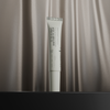 NERDS. Die 5% THD Ascorbate Brightening Eye Cream steht aufrecht vor einem seidigen, beigen Stoffhintergrund.