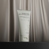 Eine Tube der NERDS. Colloidal Oatmeal Gentle Soothing Cleanser auf einer dunklen Oberfläche mit einem satinierten Hintergrund.