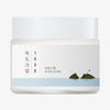 Runde, weiße Cremeverpackung der Round Lab 1025 Dokdo Cream mit minimalistischer Illustration der Dokdo-Inseln und koreanischer Flagge auf hellem Hintergrund.
