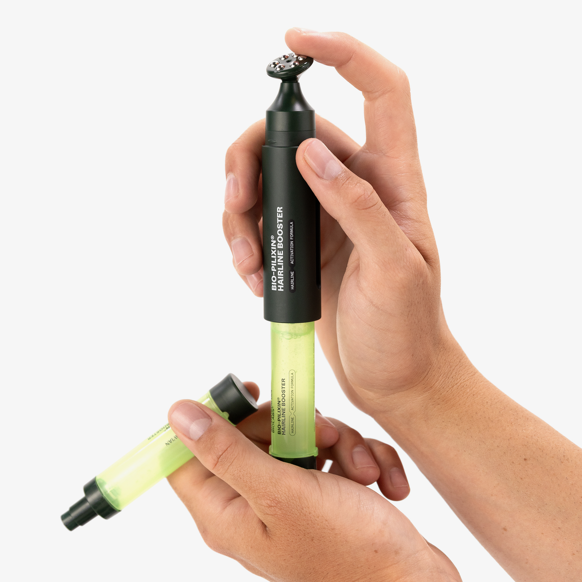 Zwei Hände halten zwei grüne Kartuschen mit einem dunkelgrünen Applikator, auf dem die Aufschrift Bio-Pilixin® Hairline Booster von Scandinavian Biolabs zu sehen ist.