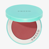 Eine türkisfarbene Kosmetikdose von SWEED, die „Air Blush Cream“ enthält, ein rotbraunes Make-up-Produkt.