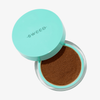 Ein türkisfarbener Behälter mit losem braunem Make-up der Marke „SWEED Miracle Powder“, dessen Deckel die Aufschrift „SWEED“ trägt, vor einem weißen Hintergrund.