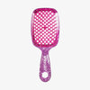 Die UNbrush Detangling Hair Brush hat ein pinkes Glitzerdesign, ein wabenförmiges Paddel und den Aufdruck "UNbrush" auf dem Griff.
