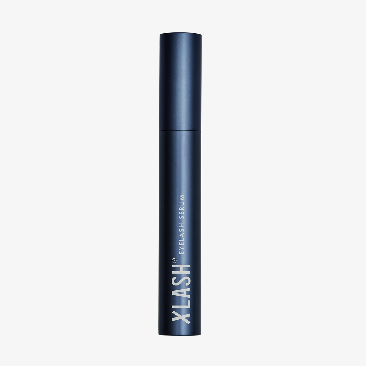 Eine dunkelblaue Tube des XLASH Xlash Wimpernseren steht aufrecht auf einem weißen Hintergrund.