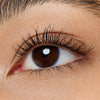 Nahaufnahme eines Auges mit brauner Iris und langen, definierten Wimpern, die mit Mascara betont wurden.