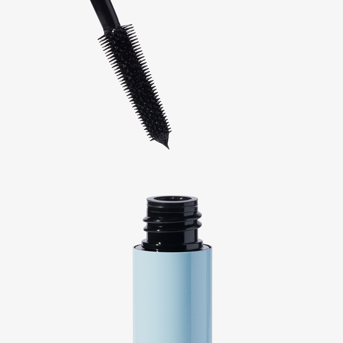 Ein „Weightless Mascara“-Applikator von XLASH wird aus einer hellblauen Tube vor einem weißen Hintergrund herausgezogen.