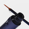 Nahaufnahme der XLASH Xlash Wimpernserum-Bürste mit einem Tropfen, die auf der geöffneten Flasche vor einem weißen Hintergrund ruht.