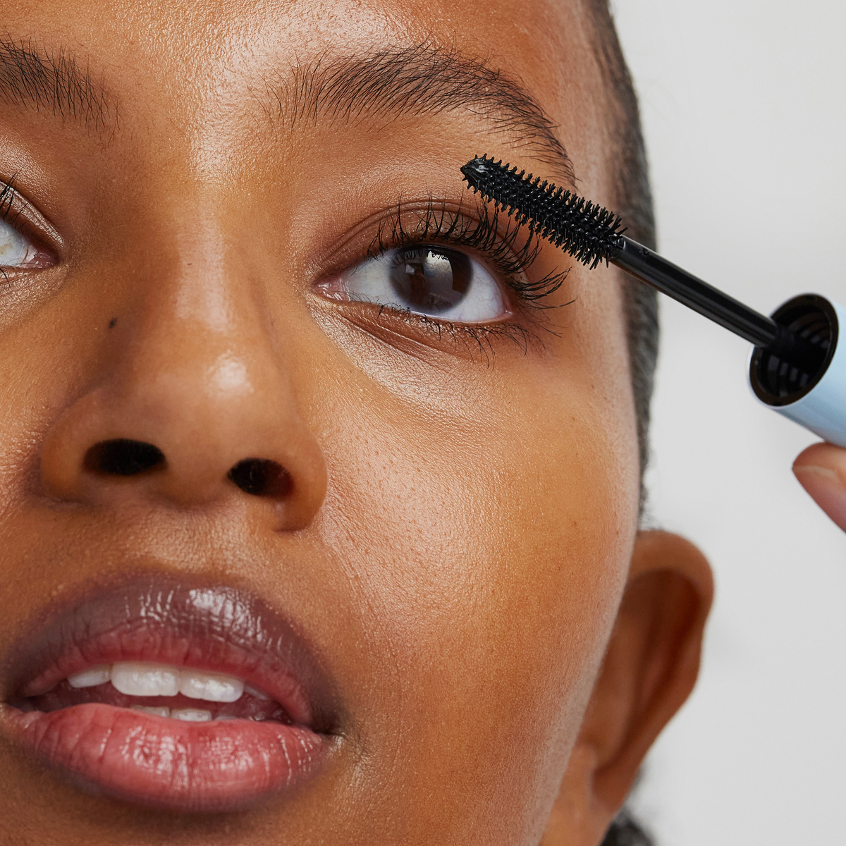 Eine Frau trägt mit einem Mascara-Bürstchen die XLASH Weightless Mascara auf ihre oberen Wimpern auf.