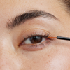 Eine Nahaufnahme einer Person, die das Xlash Eyelash Serum mit einem dünnen Pinsel auf den oberen Wimpernkranz aufträgt.