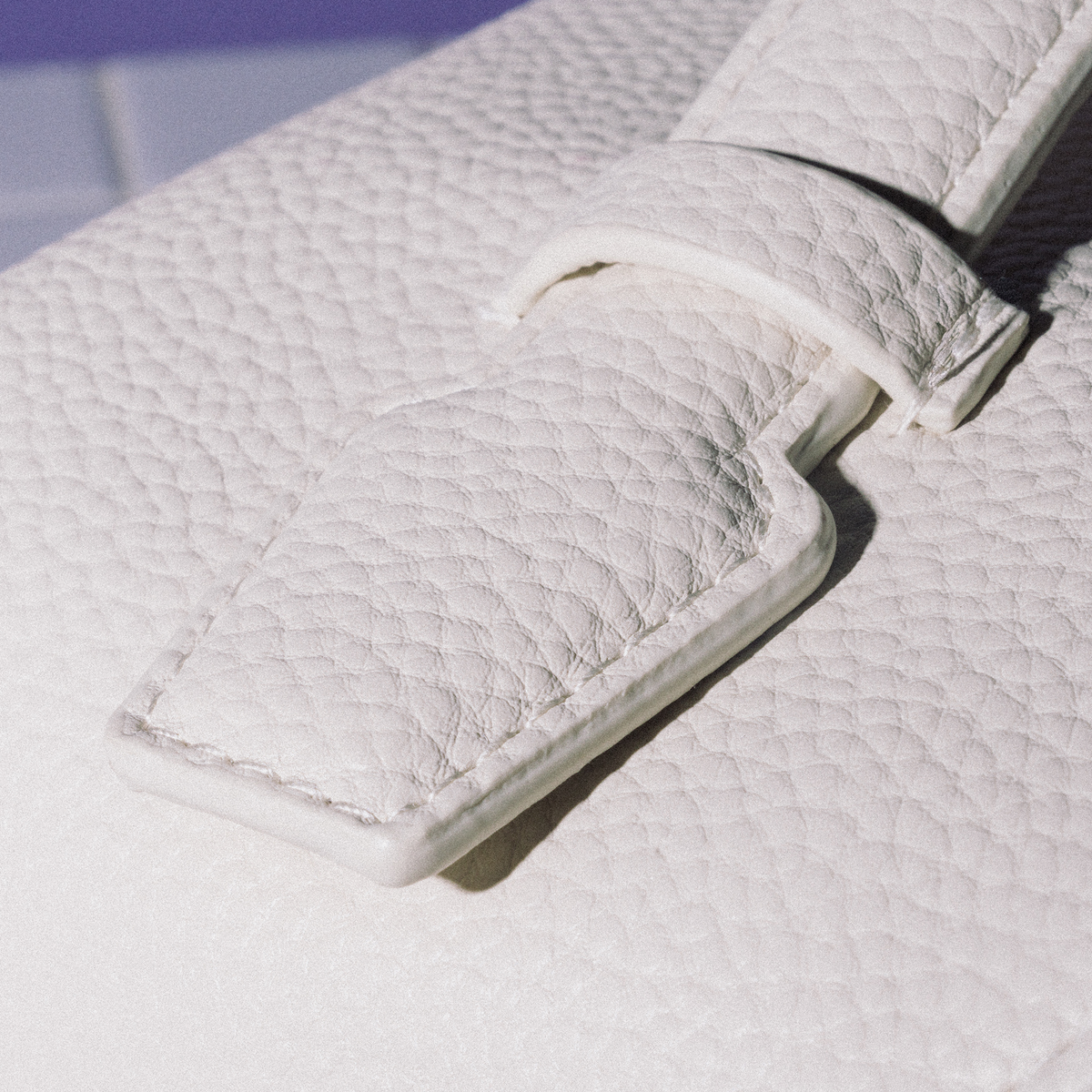 Nahaufnahme des strukturierten Riemens der PURISH Reisetasche – Cream mit Ziernähten und Schlaufe, aufgenommen bei hellem Licht.