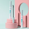 Drei Essence Curl Fixing Lash Base Mascara in Weiß mit gebogenem Bürstchen, auf rosa Podesten vor pastellblauem Hintergrund arrangiert.