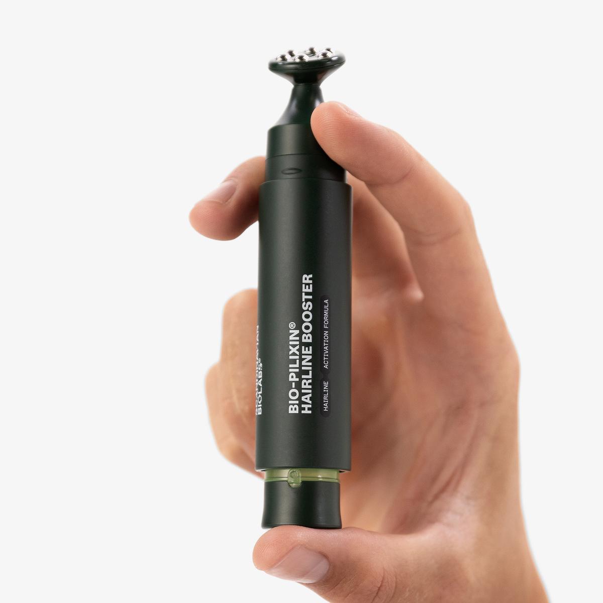 Eine Hand hält dunkelgrünen Applikator mit der Aufschrift Bio-Pilixin® Hairline Booster mit einer Applikatorspitze mit Stahlkügelchen von Scandinavian Biolabs.